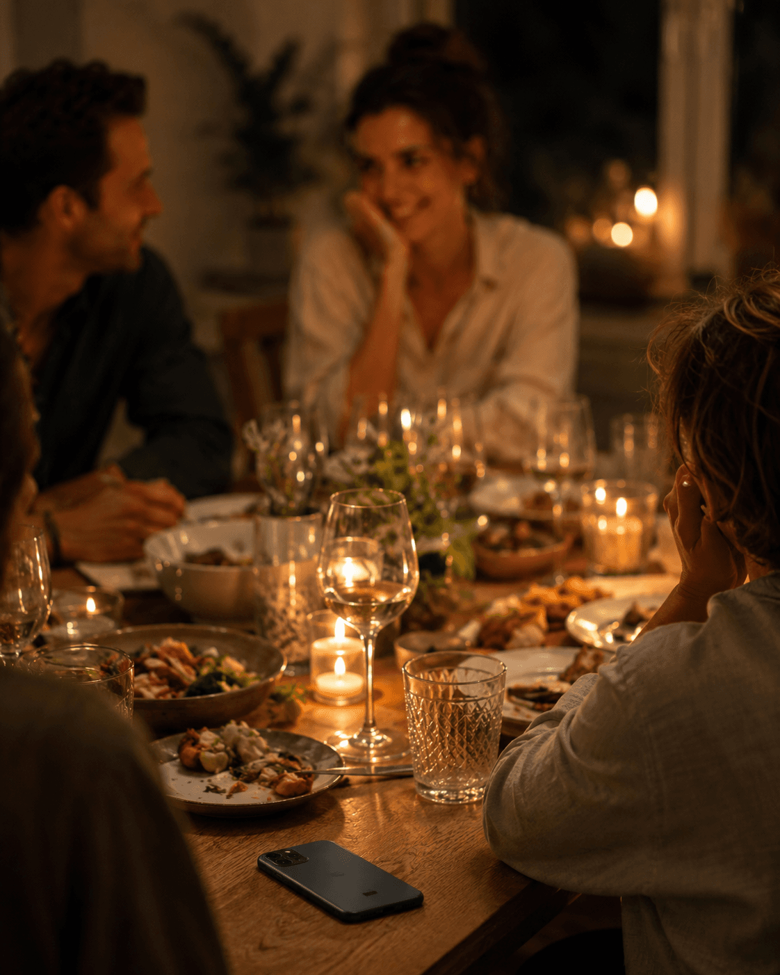 Dinner with friends — a warm table, plates and glasses, evening (real)