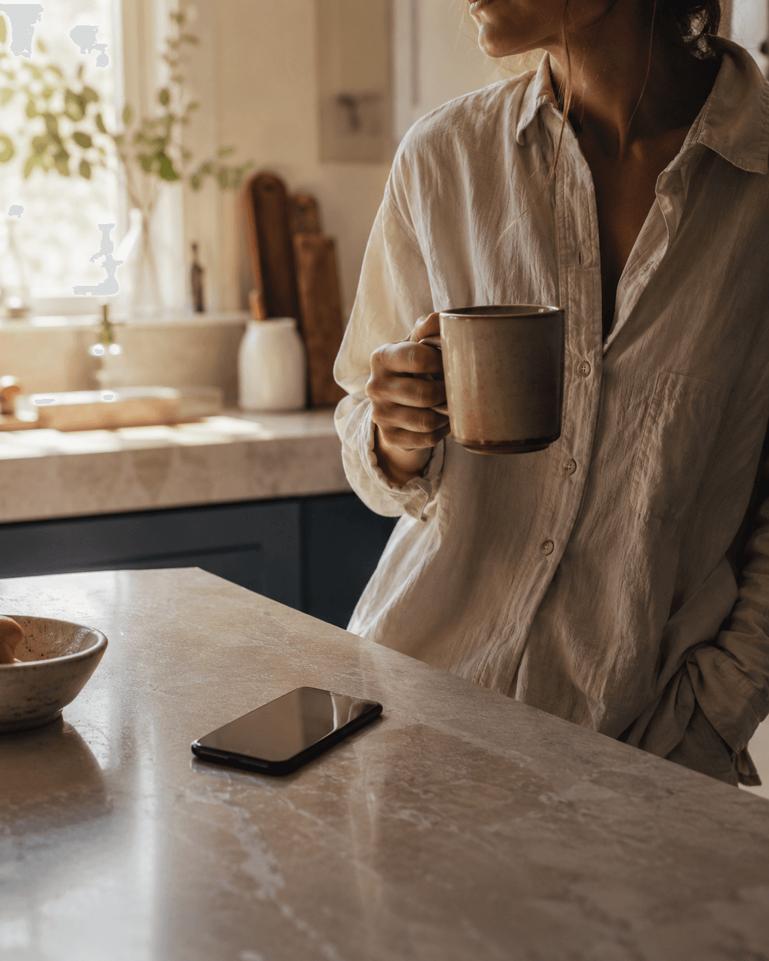Morning kitchen — coffee in hand, phone on the counter, daylight (real, candid)
